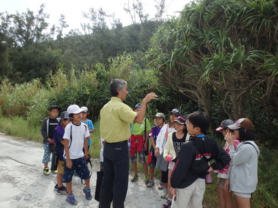 生息場所で子供達にトラップの説明をする保護官