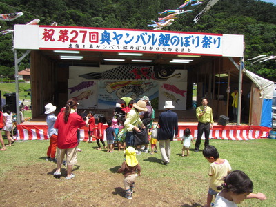 奥川の川辺に設けられた特設ステージの前で、参加者の皆さんに駆け寄られるクイちゃん。