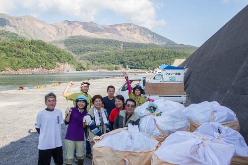 回収したゴミが入ったフレコンバックの横で記念撮影